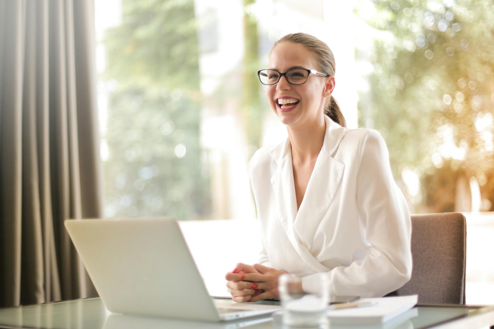 Laughing businesswoman working in office with laptop